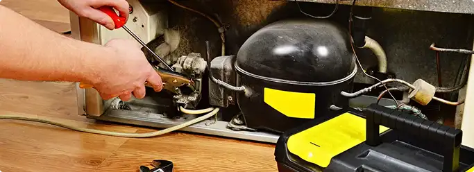 Refrigerator repair technician fixing the compressor and wiring in Bernalillo, NM