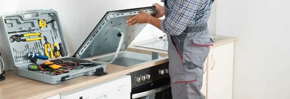 Cooktop repair technician lifting a built-in stovetop for service in Albuquerque, NM