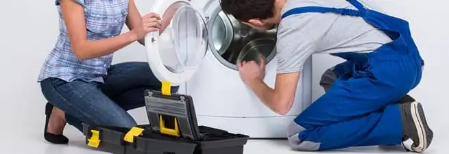 Washer repair technician inspecting a front-load washing machine with tools in Albuquerque, NM