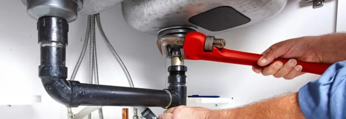 Garbage disposal repair technician tightening the sink drain and disposal connection in Albuquerque, NM