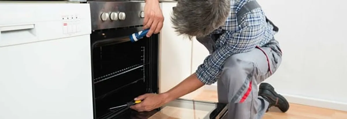 Oven repair technician inspecting and servicing an electric oven in Albuquerque, NM