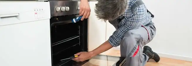 Oven repair technician inspecting and servicing an electric oven in Albuquerque, NM