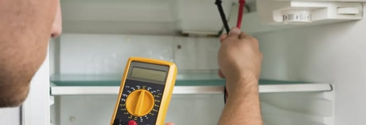 Refrigerator repair technician testing electrical components with a multimeter in Albuquerque, NM