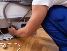 Appliance repair technician fixing refrigerator water line and connections in Albuquerque, NM