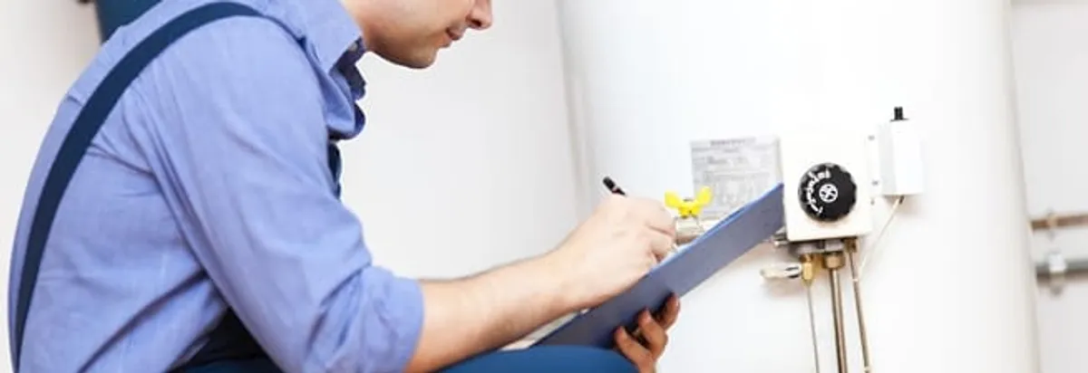 Water heater repair technician inspecting the unit and recording service notes in Albuquerque, NM