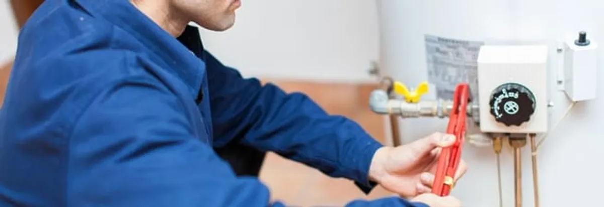 Water heater repair technician adjusting the temperature control and gas valve in Albuquerque, NM